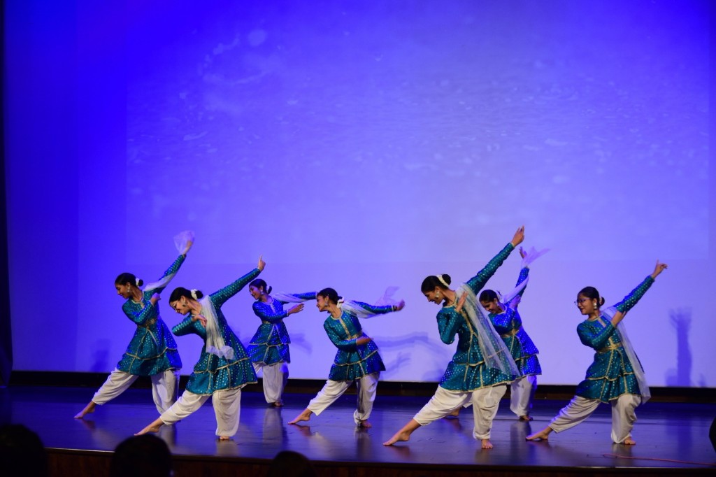 Students performing a traditional dance on a blue-lit stage during Techathlon