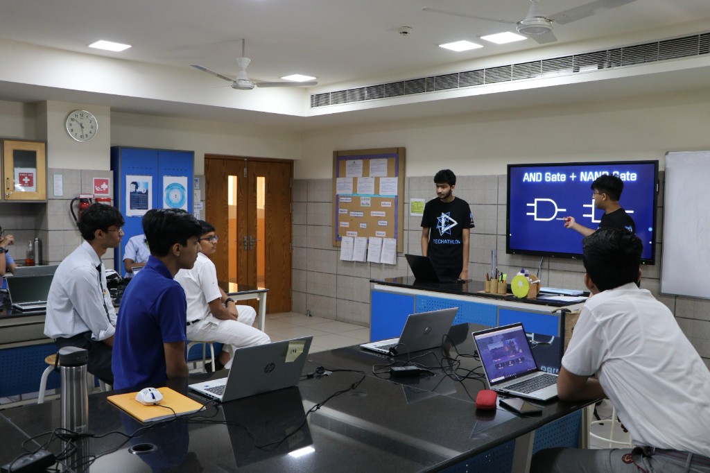 Student presenting logic gate diagrams for AND and NAND gates during a classroom session